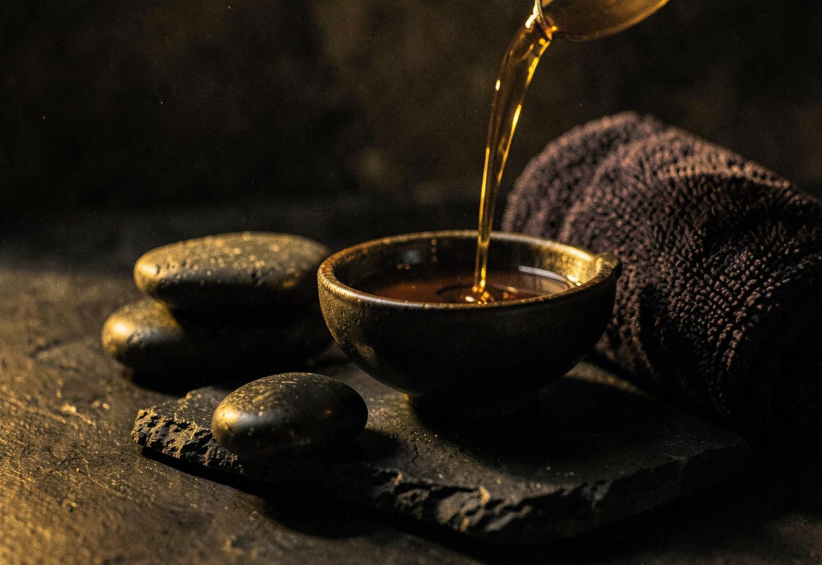 Warm treatment oil and massage stones in low golden light
